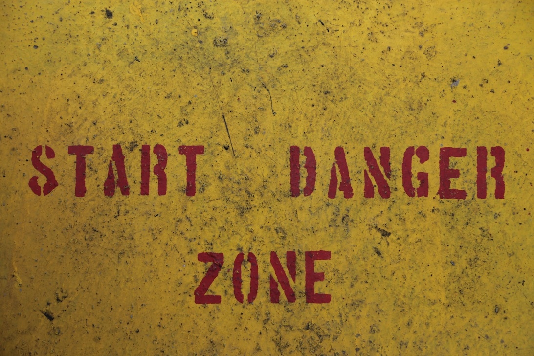 Keltainen pinta, jossa on punainen teksti 'START DANGER ZONE', symboloi yritystoiminnan riskejä ja turvallisuusprotokollia.
